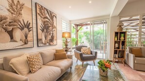 A modern living room with a beige sofa, a glass coffee table, and a bookshelf. - La Sirène du Diamant  (Le Diamant)
