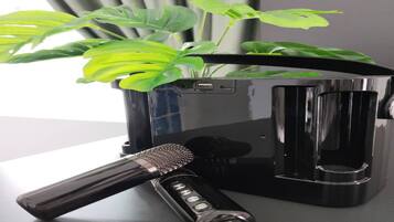 A black coffee maker, a microphone, and a green plant on a table.