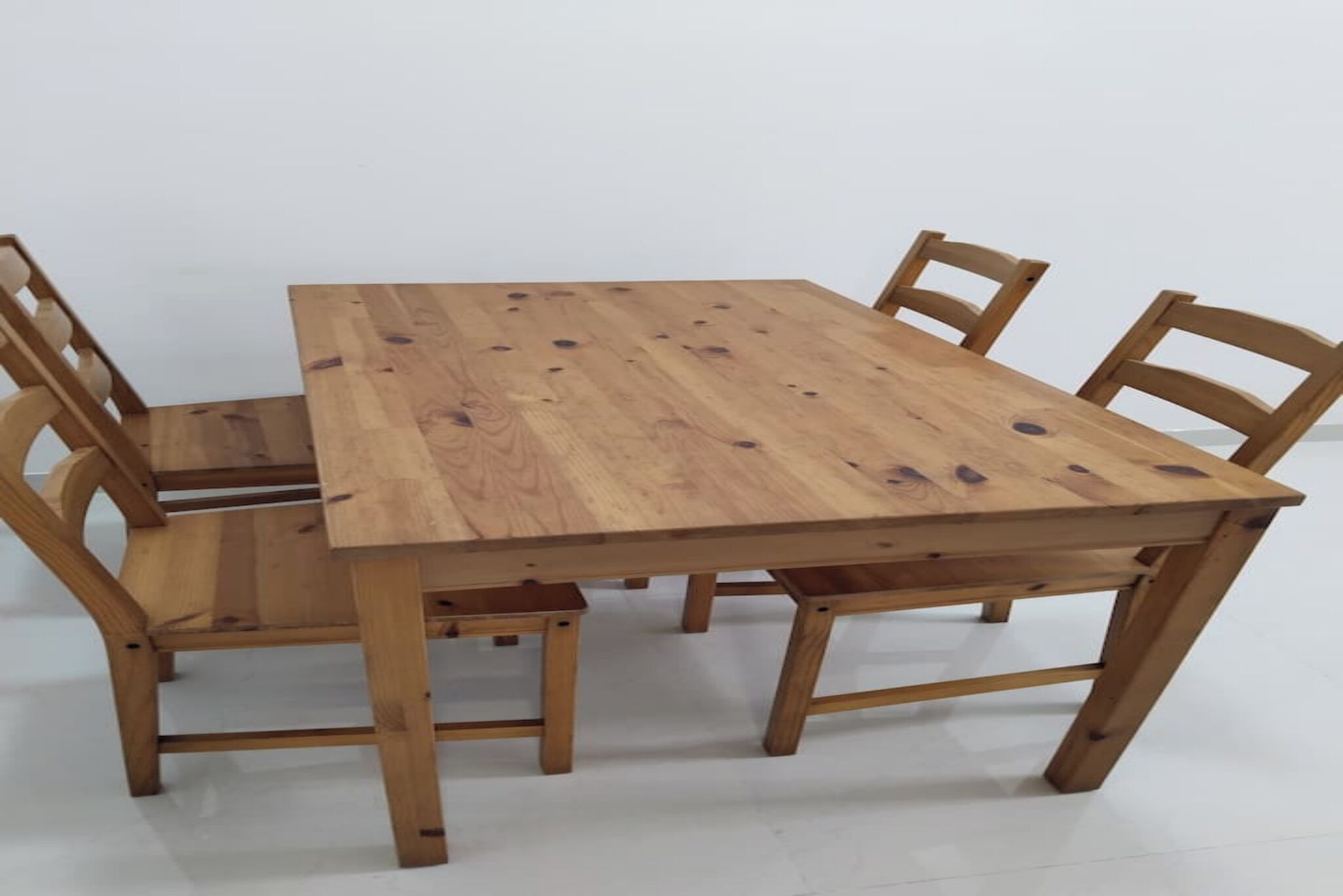 Une table de salle à manger en bois, accompagnée de quatre chaises.