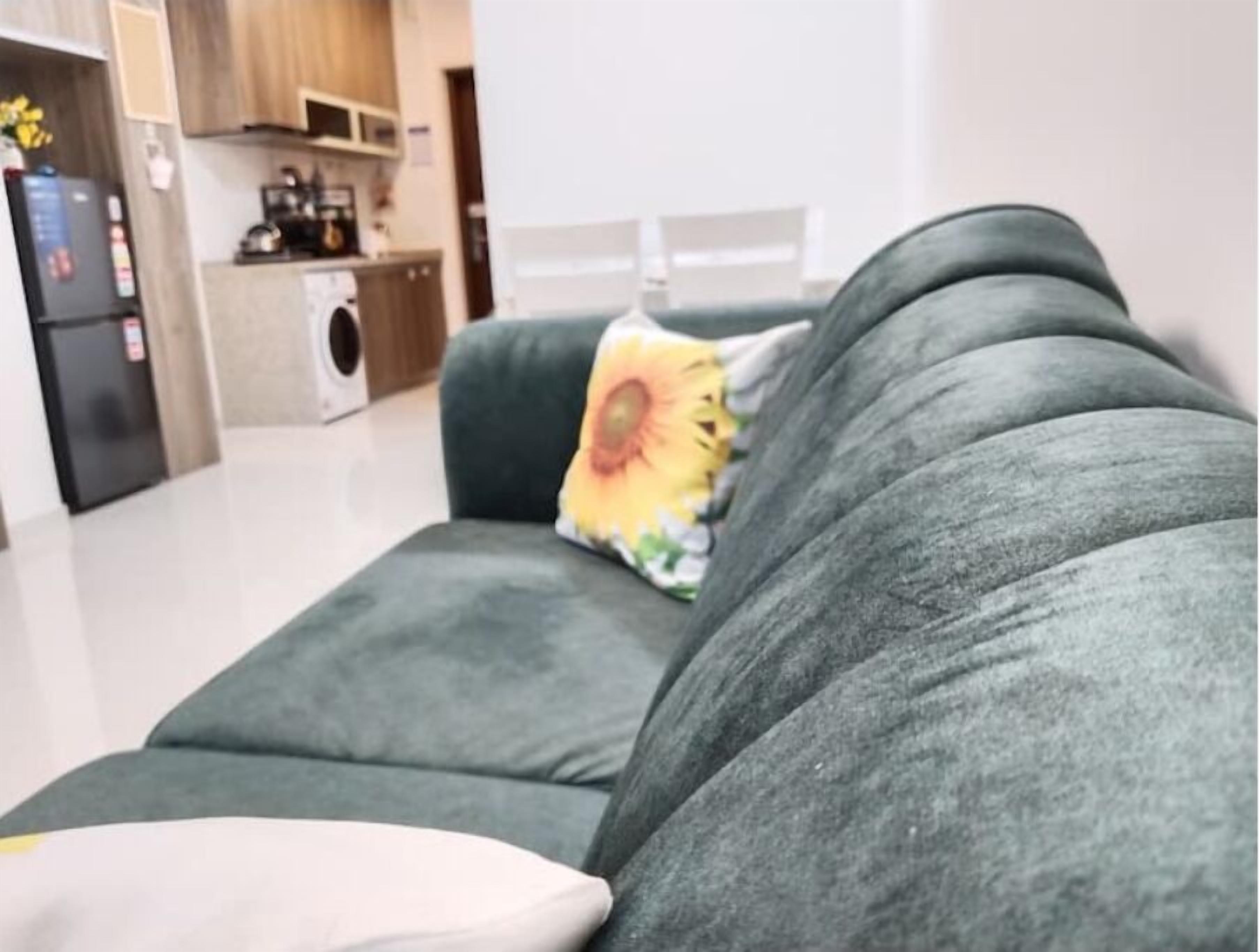 Una sala de estar moderna con un sofá gris, un cojín amarillo con diseño de girasol y un cojín blanco.