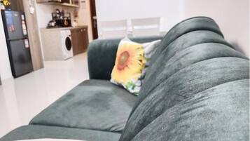 Una sala de estar moderna con un sofá gris, un cojín amarillo con diseño de girasol y un cojín blanco.