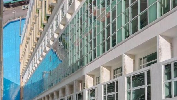 Un hotel de varios pisos con un atrio central, amplias ventanas y una piscina.