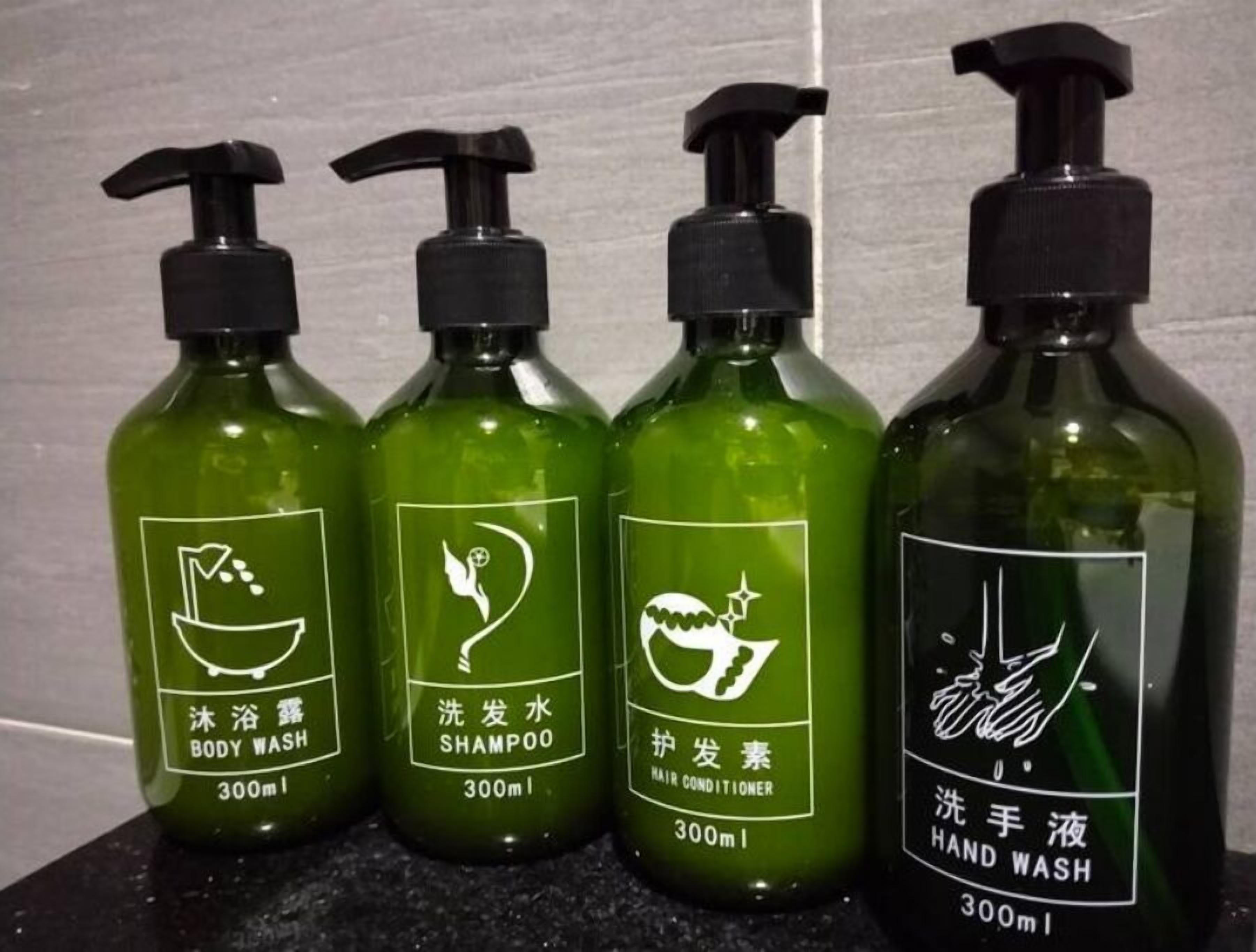 Four bottles of liquid soap with pump dispensers, each labeled with different uses such as body wash, shampoo, hair conditioner, and hand wash.