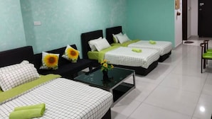 A hotel room with three beds, a ceiling fan, and a small table with a vase of flowers.