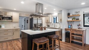 A modern kitchen with a central island, bar stools, and built-in appliances. - Breathtaking Lake Views | Private Dock, Fire Pit & Chef’s Kitchen (Hauser)