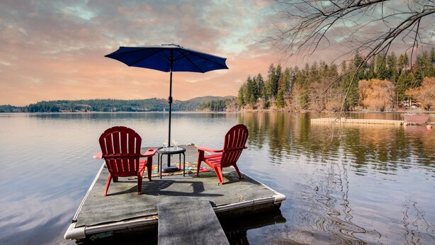 A dock with two red Adirondack chairs and a table under a blue umbrella. - Breathtaking Lake Views | Private Dock, Fire Pit & Chef’s Kitchen (Hauser)
