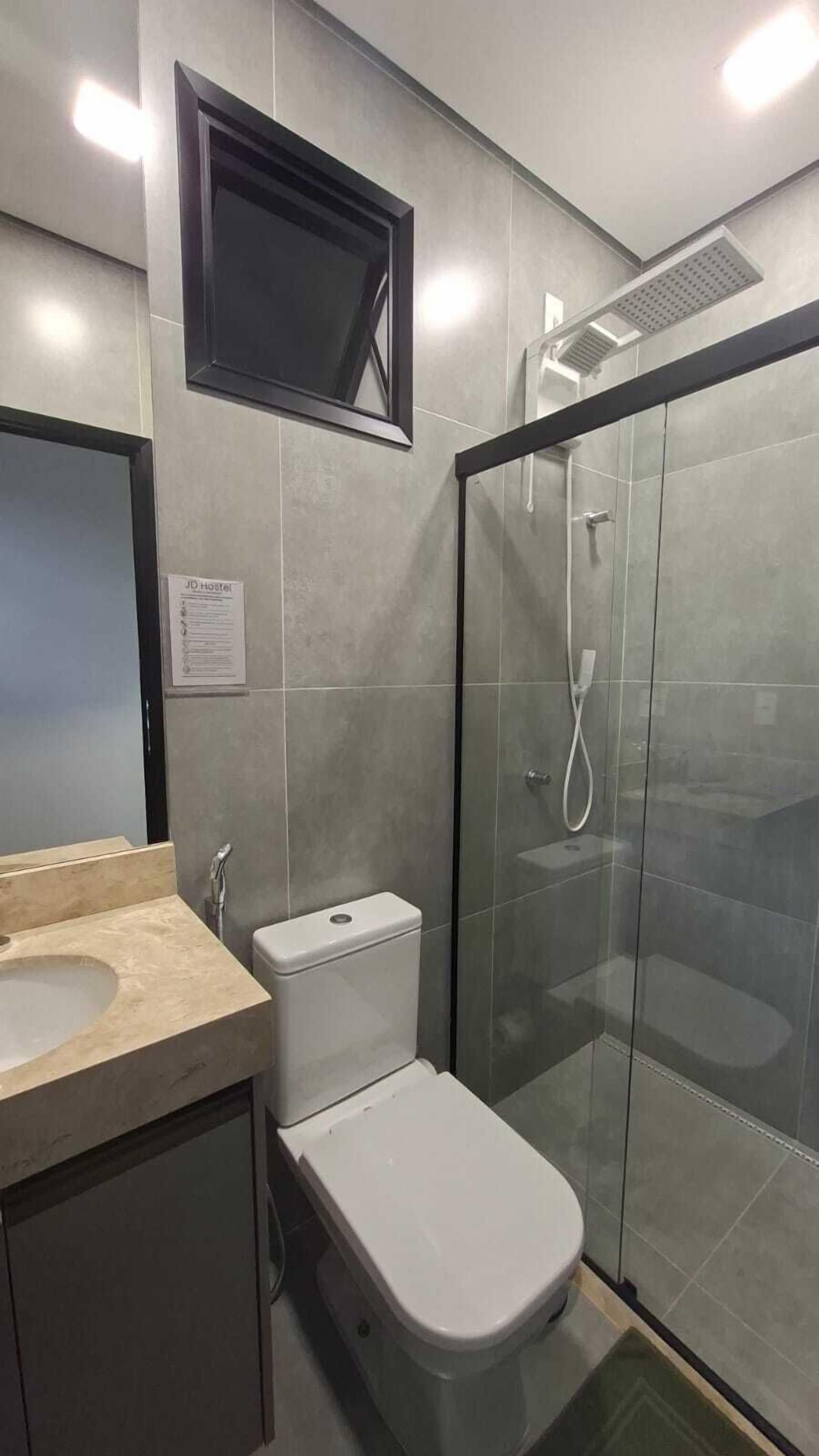 A bathroom with a toilet, sink, and shower enclosure.