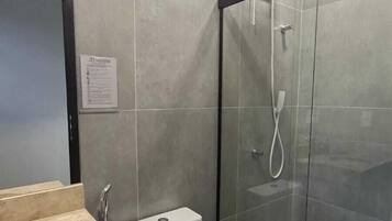 A bathroom with a toilet, sink, and shower enclosure.