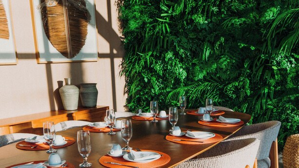 Un comedor con una mesa de madera dispuesta para seis personas, rodeada de sillas tapizadas.