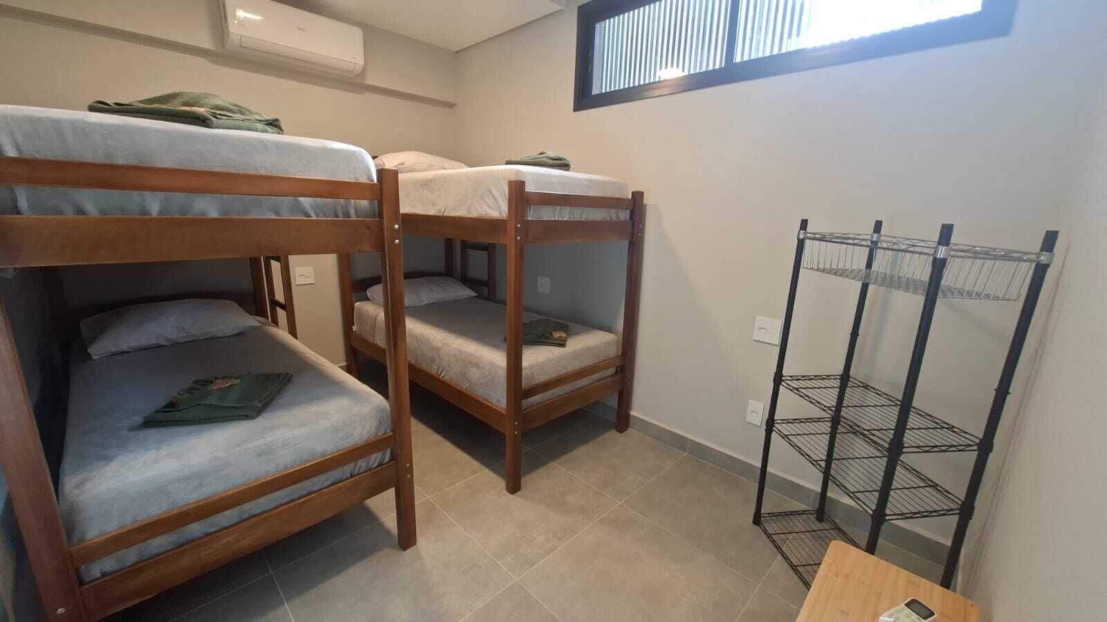 A dormitory room with bunk beds, a metal shelf unit, and a window.