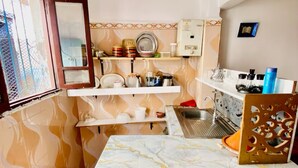 Une cuisine compacte dotée d’un plan de travail en marbre, d’un évier et d’une fenêtre avec une grille métallique.
