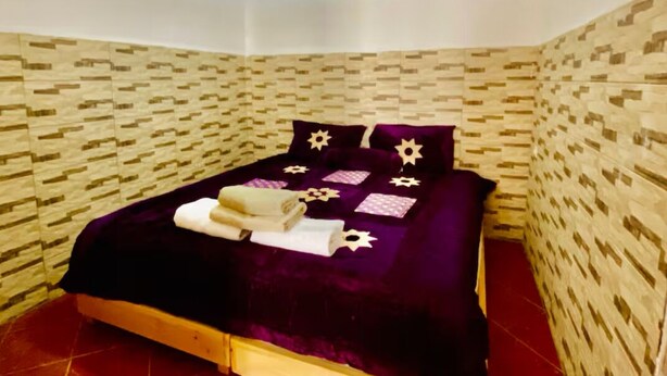 Une pièce avec un lit, un mur orné d’un motif et un luminaire suspendu.
