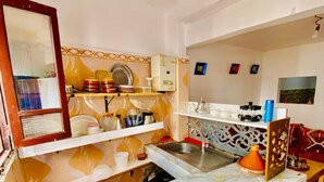 Une cuisine de taille réduite, équipée d’un évier, d’un plan de travail et de divers ustensiles de cuisine.