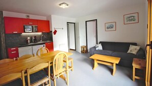 Ett kompakt bostadsutrymme med ett litet kök, en matplats och en sittgrupp.