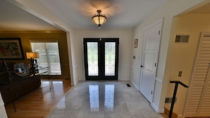 A spacious hallway with a polished floor, a chandelier, and a set of double doors with decorative glass panels. - Hershey Ranch Retreat: Spacious, luxurious, fun w/ fire pit, arcade, game room. (Hershey)