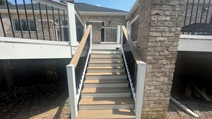 A staircase with wooden steps and white railings leading to a building with stone walls and a metal fence. - Hershey Ranch Retreat: Spacious, luxurious, fun w/ fire pit, arcade, game room. (Hershey)