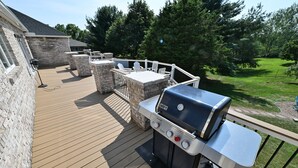 A deck with a barbecue grill, stone pillars, and outdoor seating. - Hershey Ranch Retreat: Spacious, luxurious, fun w/ fire pit, arcade, game room. (Hershey)