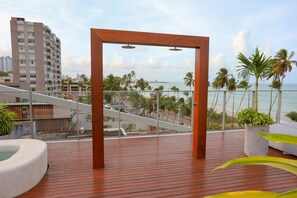A wooden deck with a view of the beach and palm trees.