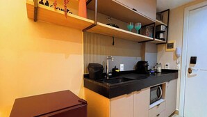 Una cocina compacta con un lavamanos, una cafetera y un microondas.