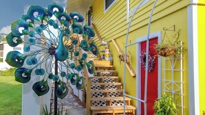 A yellow building with a red door and a staircase leading to the entrance. - The Sunburst Oasis  (Palm Harbor)