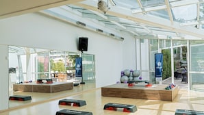 A modern gym with exercise equipment, large mirrors, and a glass ceiling.