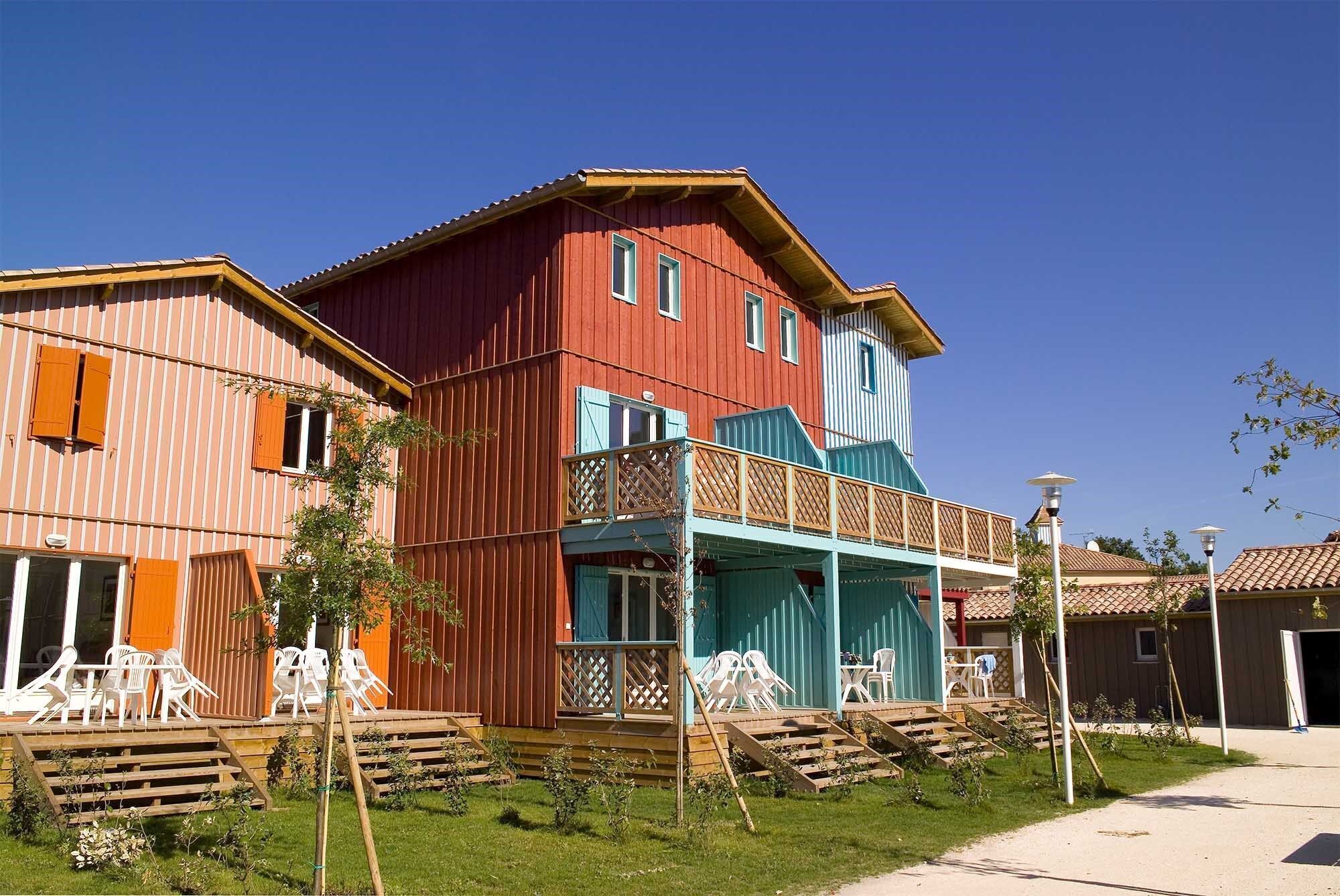 Un bâtiment en bois à deux étages, doté d’un balcon, de sièges en plein air et surplombant un ciel dégagé.