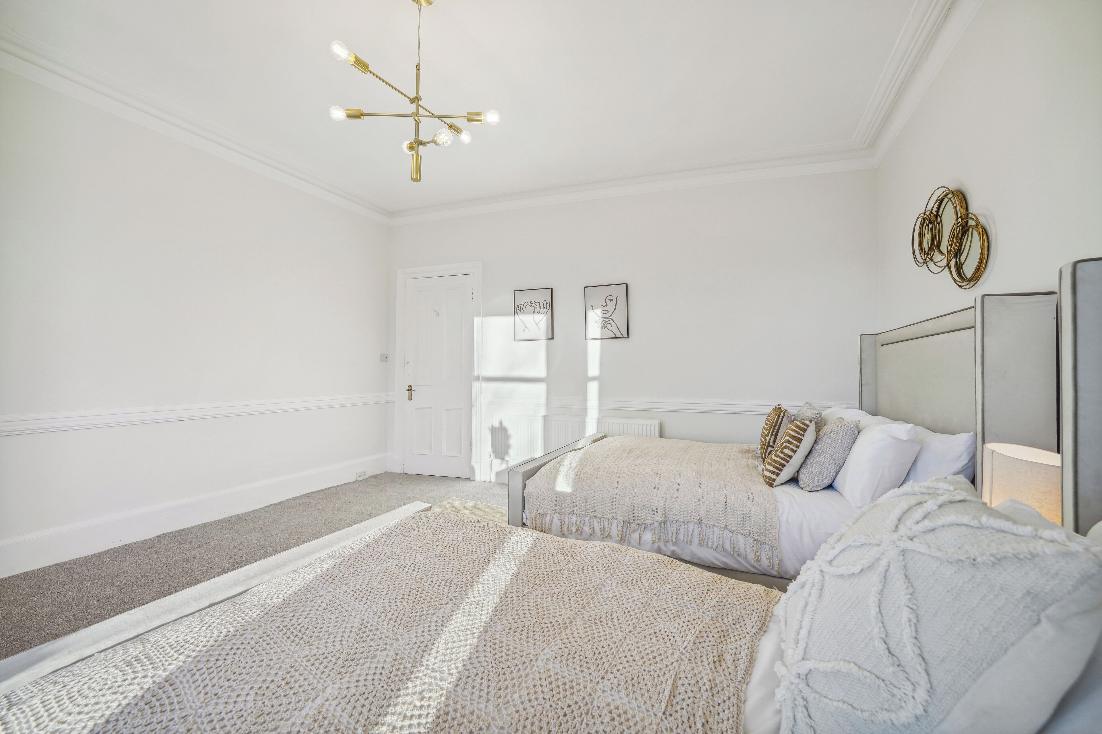 Une chambre à coucher comprenant un lit, une table de chevet, une lampe et un luminaire au plafond.