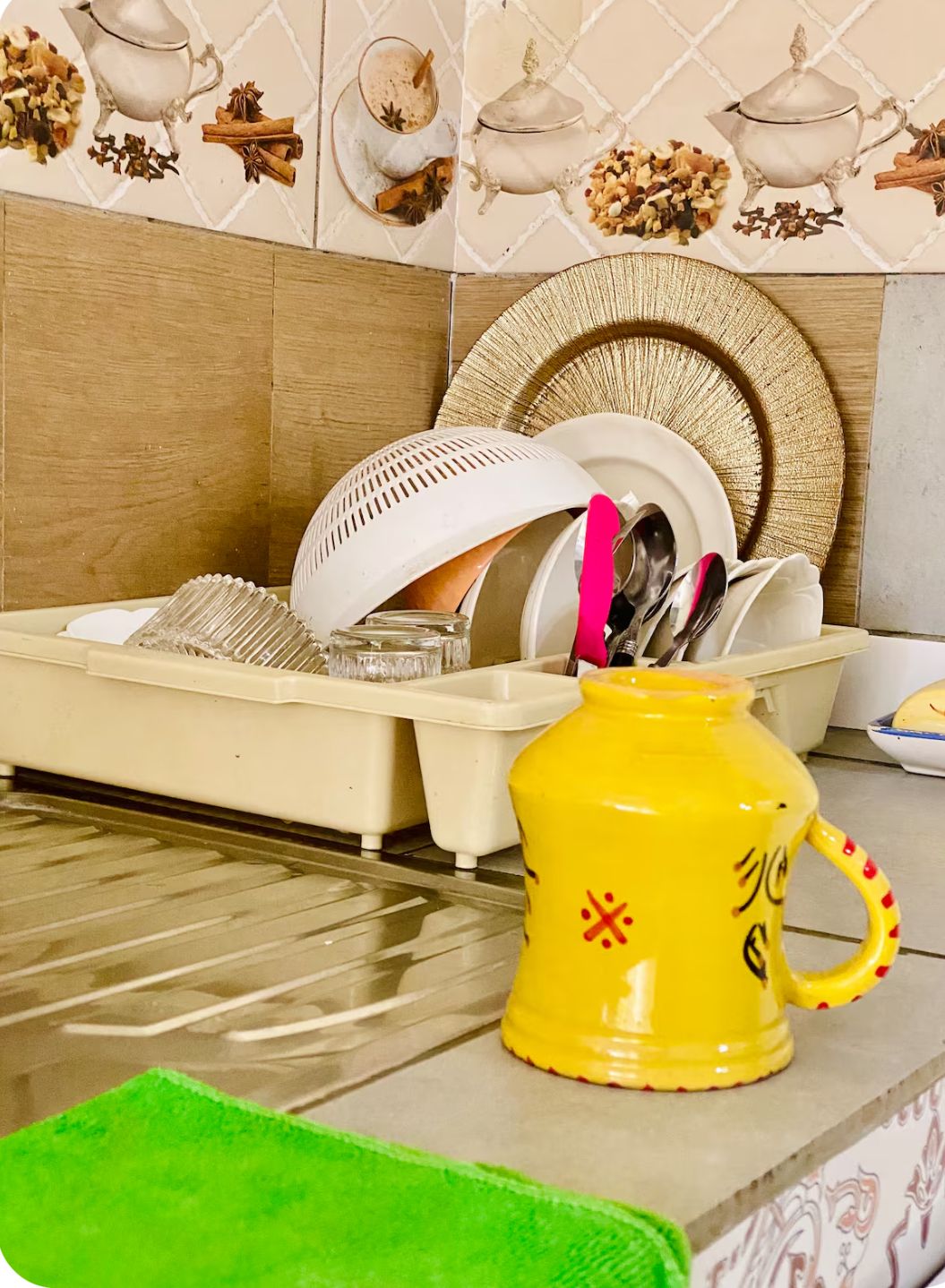 Une cuisine avec un égouttoir à vaisselle, une tasse jaune avec une anse et un set de table en fibres tressées.