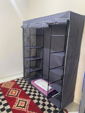 A room with a grey storage unit against a wall, a patterned rug on the floor, and a partially visible door.
