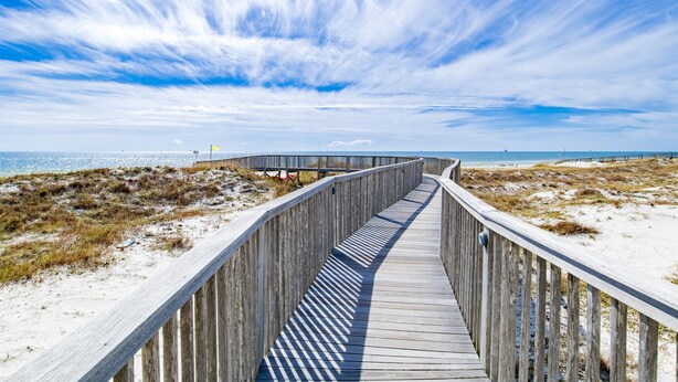 Un muelle de madera que conduce a una playa con cielo despejado.