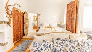 A bedroom with a large bed, a wooden door, and a small table. - Maison De Yaya at Heraion Lagoon (Loutraki-Agioi Theodoroi)
