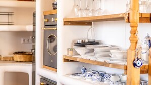 A kitchen with white cabinets, wooden shelves, and a built-in oven. - Maison De Yaya at Heraion Lagoon (Loutraki-Agioi Theodoroi)