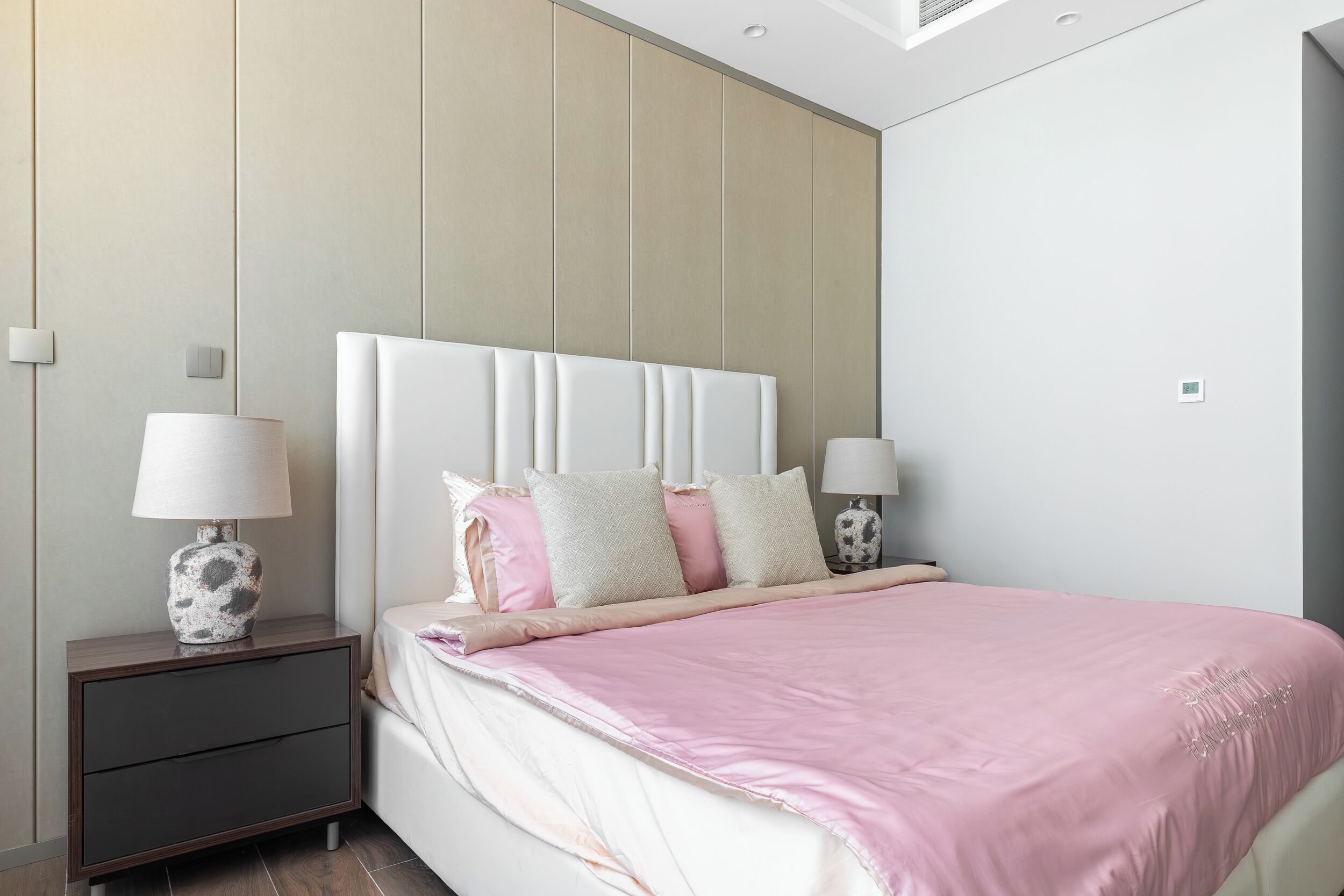 A modern bedroom with a large bed, two bedside tables, and a nightstand.