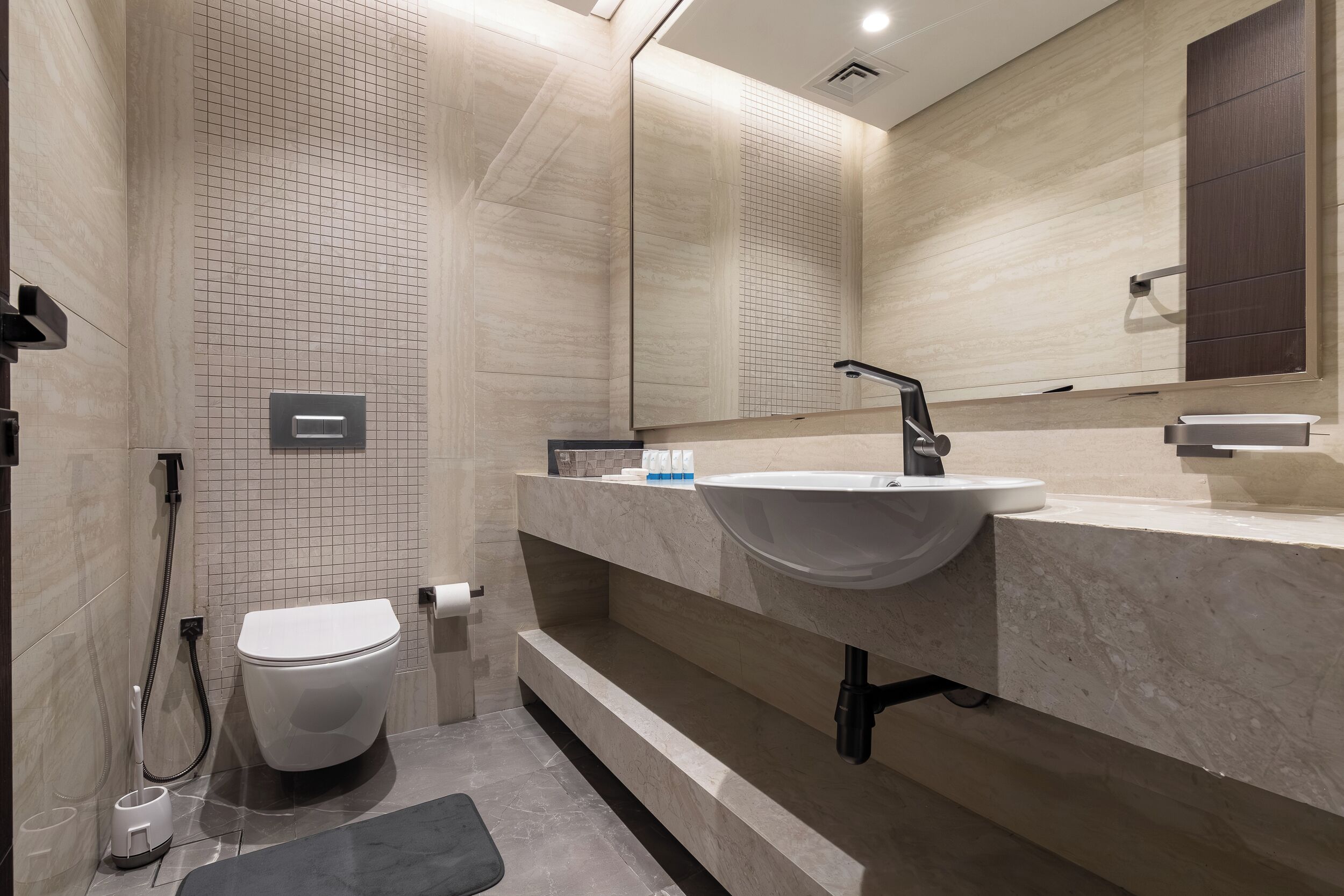 A modern bathroom with a toilet, sink, and mirror.