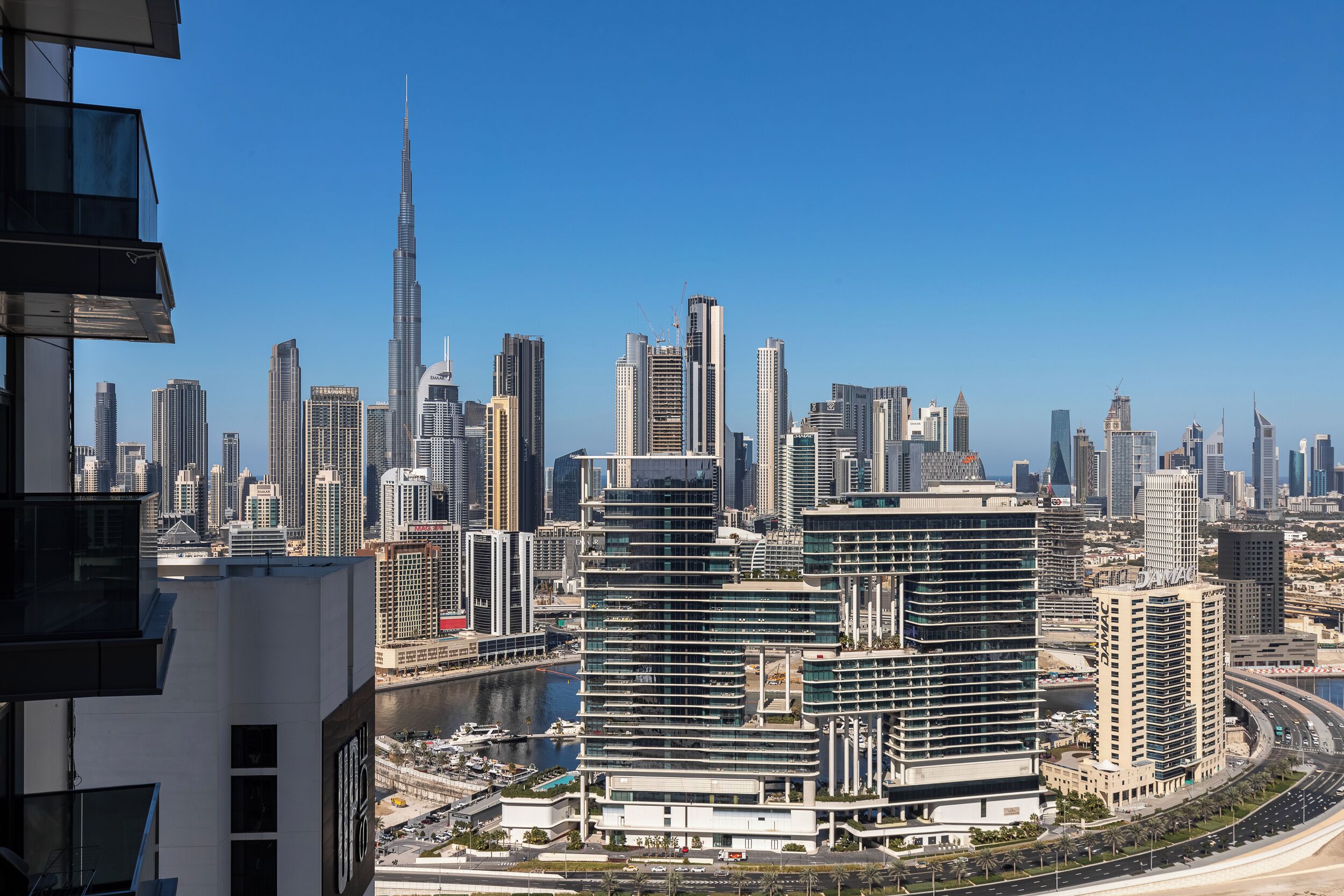 A cityscape with modern high-rise buildings, a prominent skyscraper, and a river.