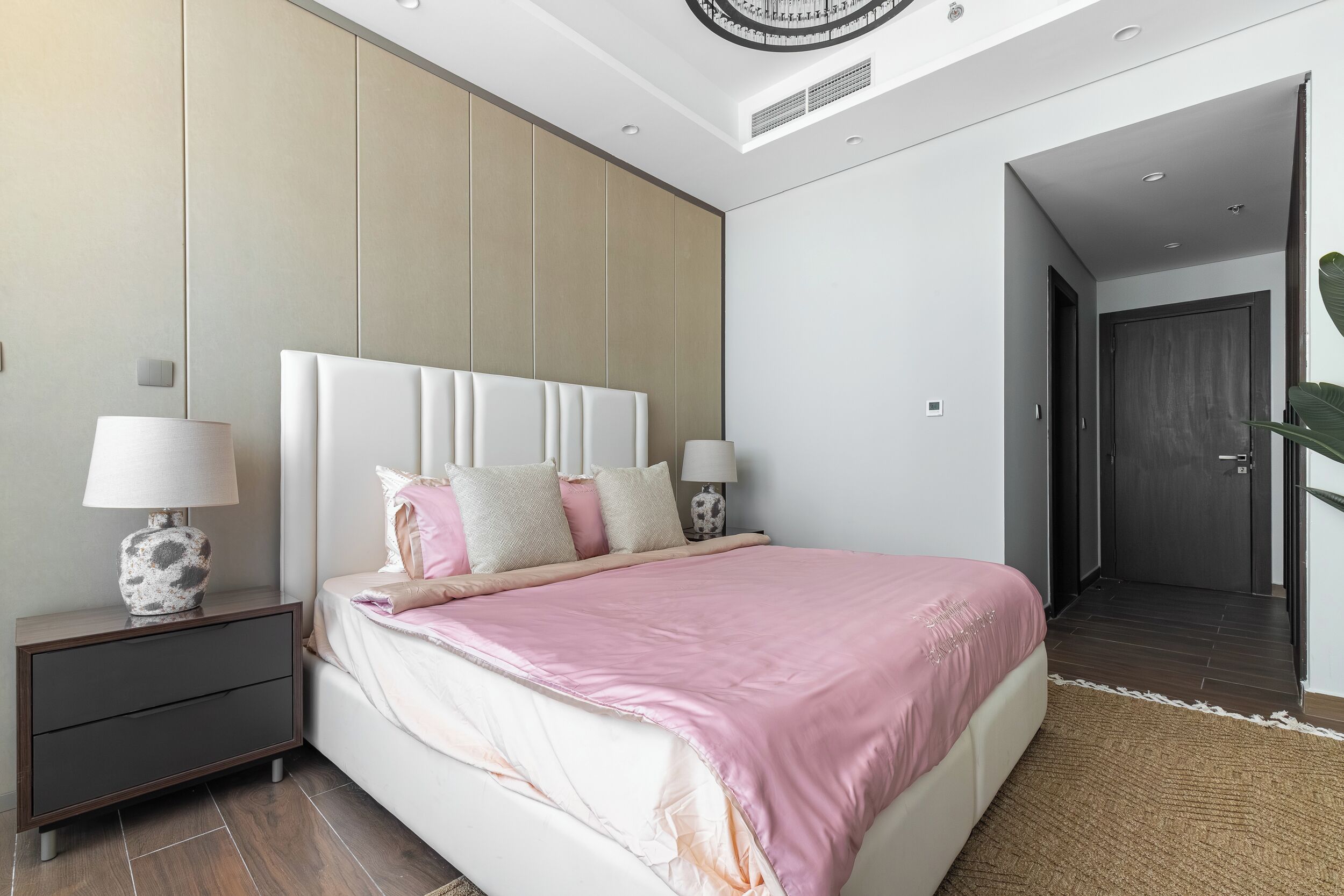 A modern bedroom with a large bed, bedside tables with lamps, and a neutral color scheme.