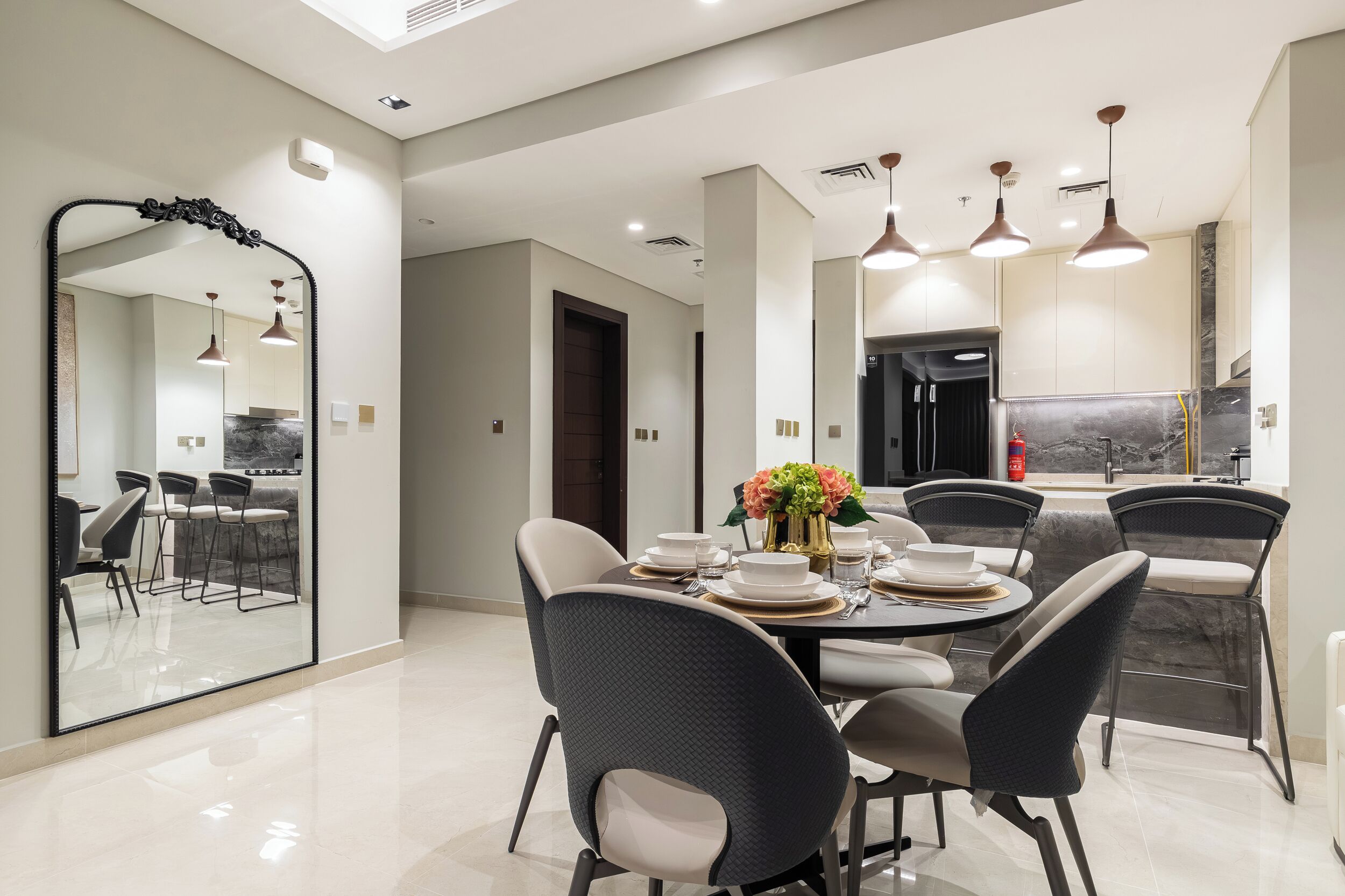 A modern dining area with a large mirror, a round table set for four, and contemporary chairs.