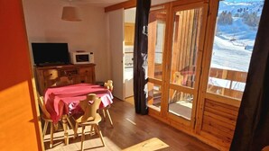 A dining area with a table set for four, wooden flooring, and a view of a snowy landscape through a glass door. - Ski-in/ski-out & foot of the slopes, 5th floor, view ski slopes, balcony, tv, 28m², La Plagne (La Plagne)