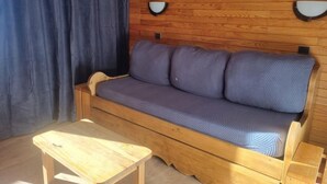 A wooden sofa with a cushion, a wooden table, and a wooden wall with two wall-mounted lights. - Ski-in/ski-out & foot of the slopes, 5th floor, view ski slopes, balcony, tv, 28m², La Plagne (La Plagne)
