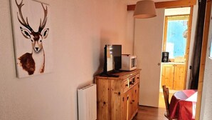 A bedroom with a bed, a wooden dresser, a microwave, and a table with a red tablecloth. - Ski-in/ski-out & foot of the slopes, 5th floor, view ski slopes, balcony, tv, 28m², La Plagne (La Plagne)