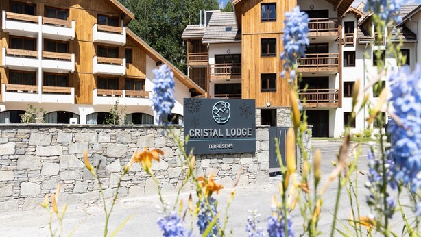 A sign for Cristal Lodge with a stone wall and wooden buildings in the background. - Chalet in Chantemerle With Sunny Ski Slopes (Saint-Chaffrey)