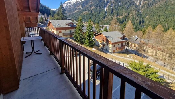 A balcony with a view of a mountain range and a village below.