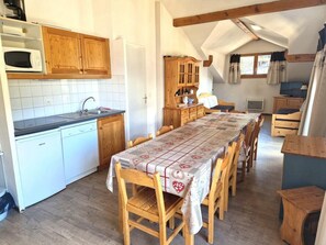 A cozy kitchen with wooden cabinets, a white dishwasher, and a dining table with chairs.