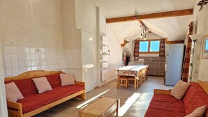 A cozy living room with two wooden sofas and a coffee table, a kitchen area with a dining table, and a small kitchenette. - 100m from ski slopes, 2nd floor, balcony, ski locker, 90m², Valfréjus (Valfréjus)