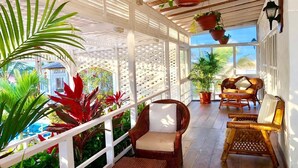 A covered outdoor area with wicker furniture, potted plants, and a view of a pool. - Beautiful Oceanfront Home in Zorritos - Just 2 Hours from Tumbes Airport (tumbes)