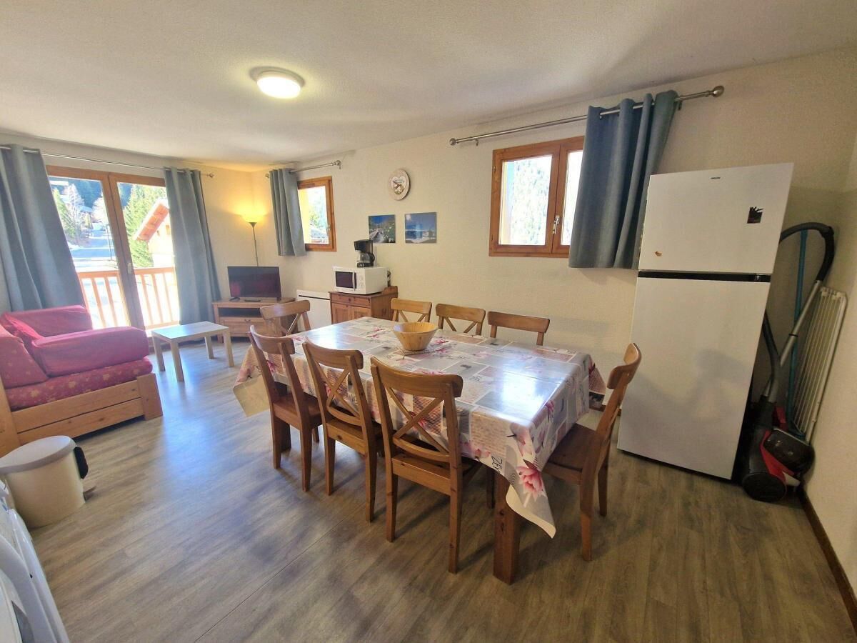 A cozy dining area with a table, chairs, and a refrigerator.