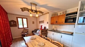 A kitchen with a wooden table, white cabinets, and a microwave.