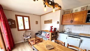 A cozy room with a wooden dining table, a sofa, and a kitchen area with white cabinets and a dishwasher.