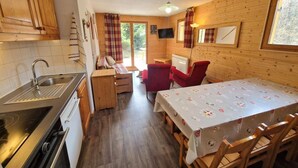 A compact kitchen with wooden cabinets, a sink, and a dining area with a table and chairs. - 100m from ski slopes, terrace, ski locker, 48m², Valfréjus (Valfréjus)