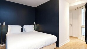 A bedroom with a bed, dark walls, and a window. - PARISIAN ESCAPE NEXT TO THE LOUVRE AND PALAIS ROYAL - RUE SAINT-HONORÉ (Paris)
